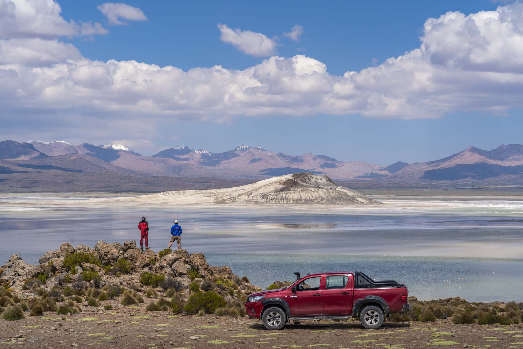 Zwei Männer und ein Geländewagen stehen am Ufer des Salzsees Salar de Surire im Norden Chiles.